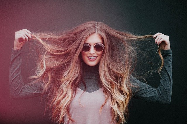 femme châtain qui sourie avec lunettes de soleil